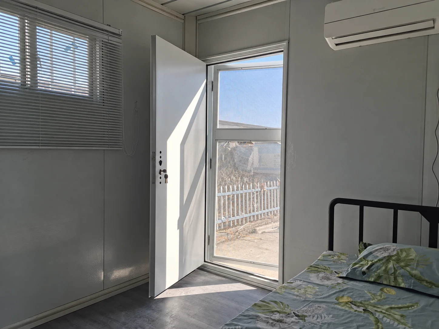 Aménagement intérieur type d'une chambre avec un lit simple, des stores, une entrée ouverte et un climatiseur mural. Référence d'aménagement intérieur.
