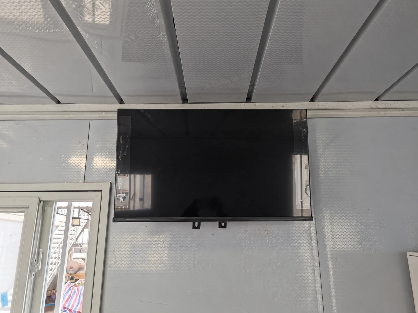 Vue de face d'un téléviseur mural au-dessus d'une fenêtre dans une pièce modulaire type. Référence des composants.