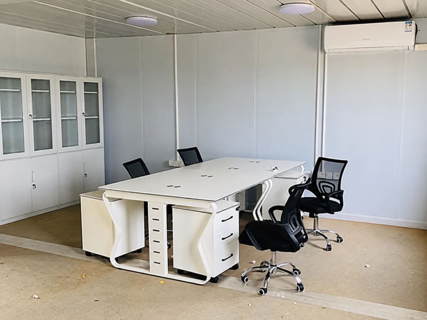 Referenzbüro-Interieur mit gruppierten Schreibtischen, Bürostühlen und einem Aufbewahrungsschrank.