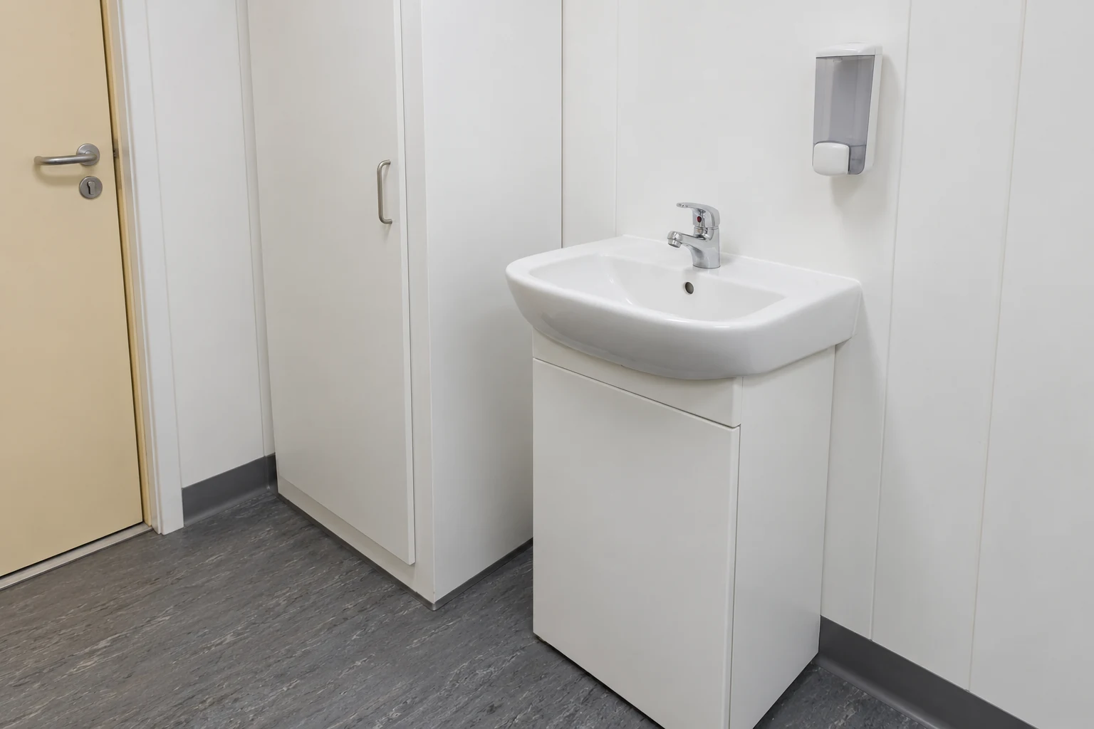 A complete washbasin and closed service cupboard illustrate supply interfaces to confirm.