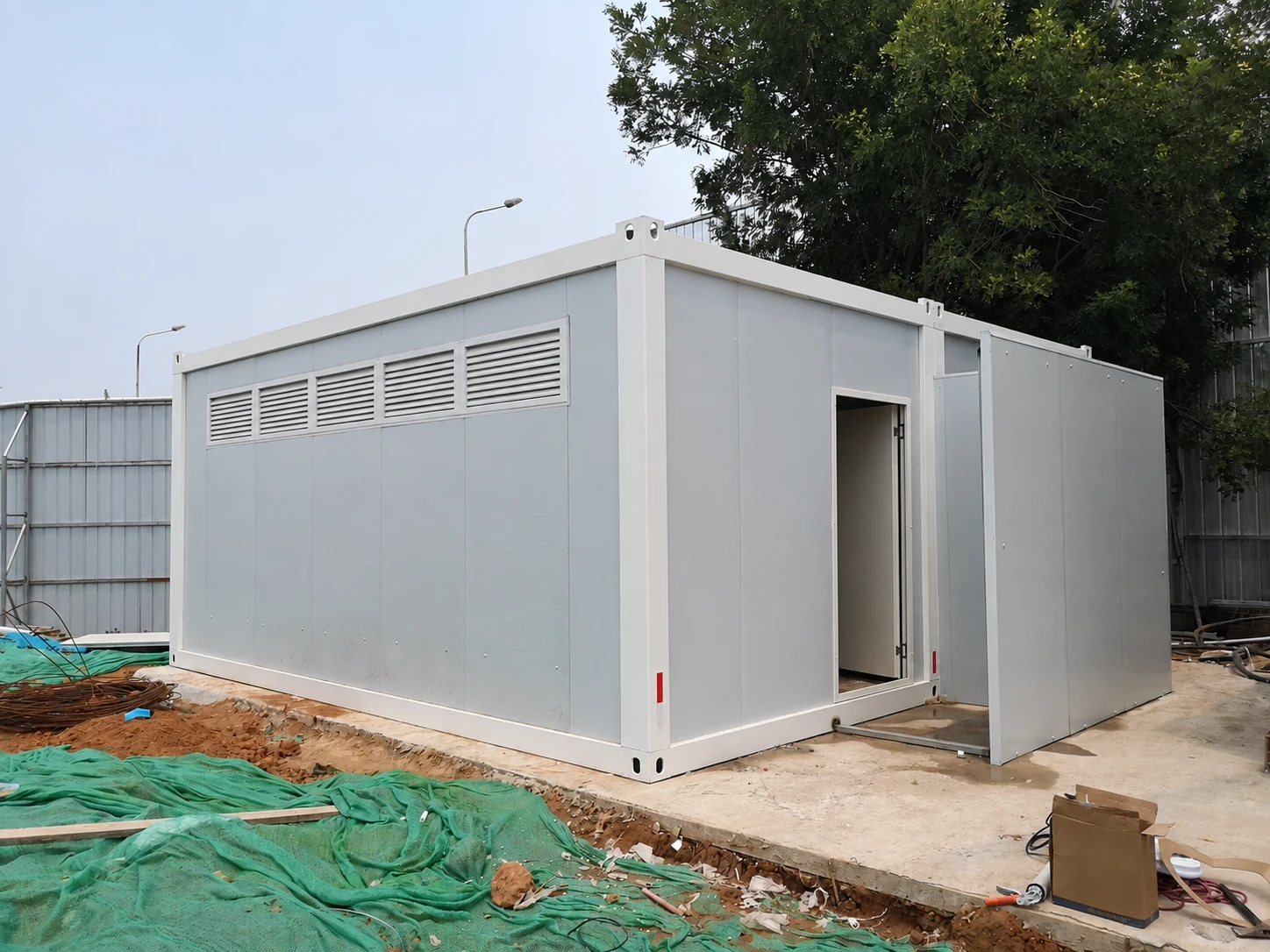 White sanitation block with a row of high wall vents and an open door; exterior reference.