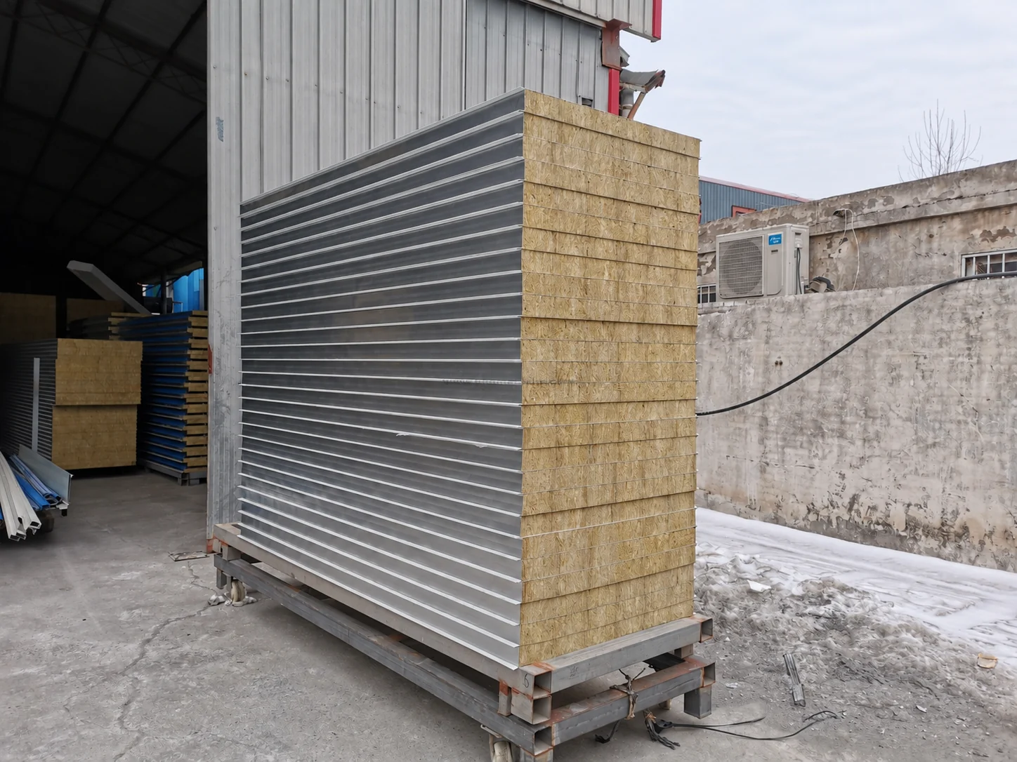 Pile de panneaux à parement métallique avec bords isolants apparents à l'extérieur d'un atelier. Échantillon de matériau de référence.